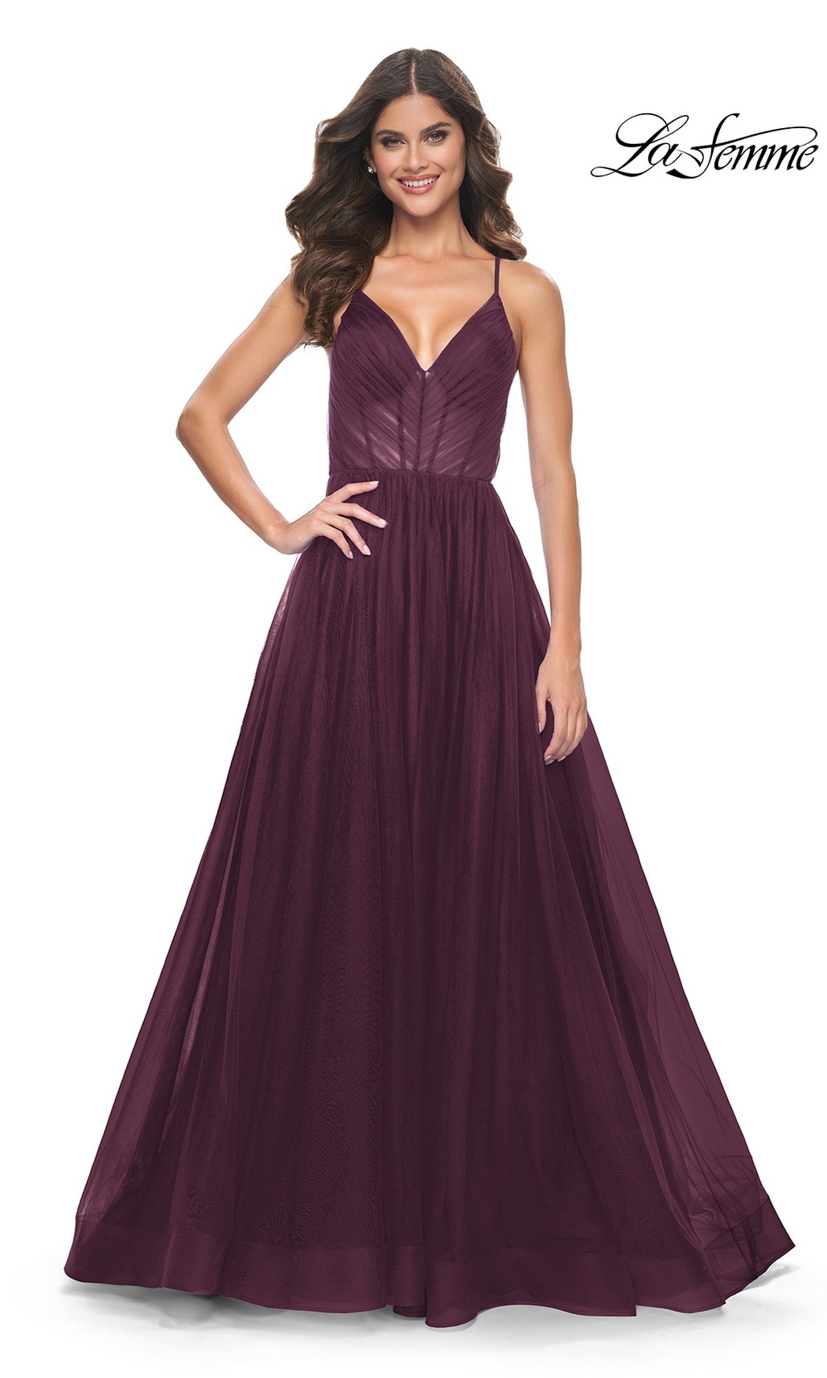 Woman poses in the La Femme Sheer-Waist Long Prom Ball Gown 31457, a sleeveless burgundy A-line dress with a fitted bodice and flowing skirt, smiling against a white background. La Femme logo appears in the top right corner.